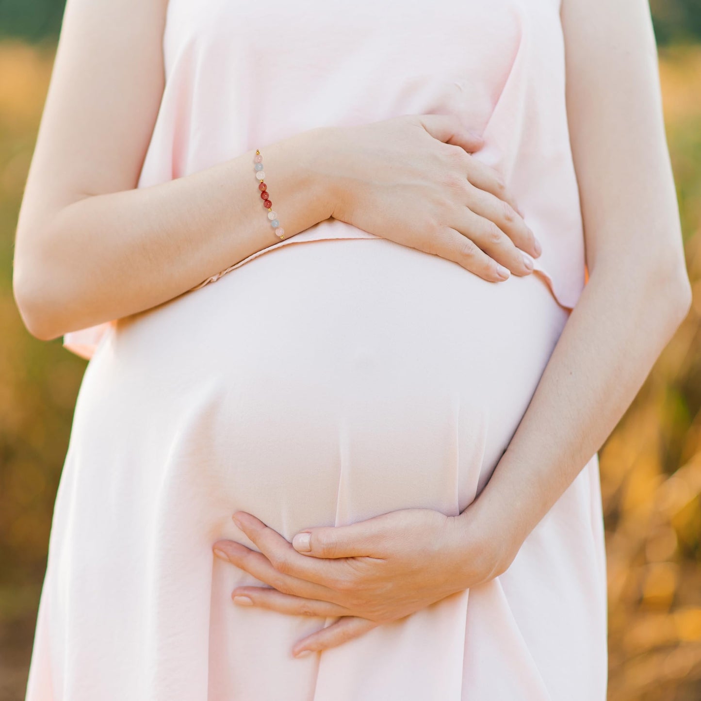 a pregnant woman wearing adjustable beaded energy bracelets with rose quartz, aquamarine, moonstone and rhodonite.