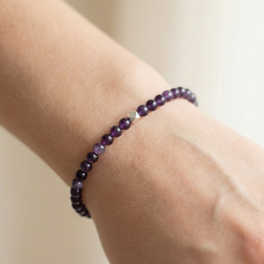 A woman wearing a 4mm Amethyst Elastic Beaded Energy Bracelet.