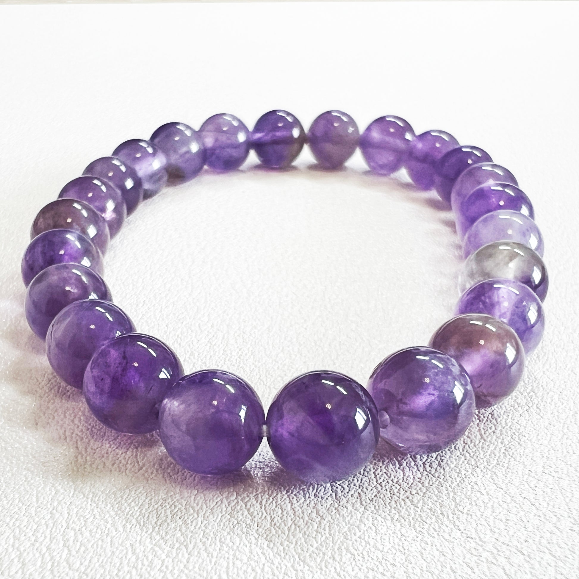 Detailed shot of a 8mm crystal bead bracelet with natural amethyst texture.