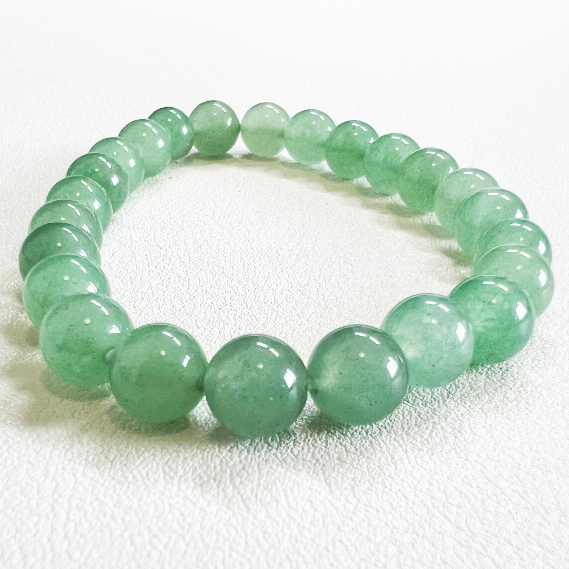 Detailed shot of a 8mm crystal bead bracelet with natural green aventurine texture.